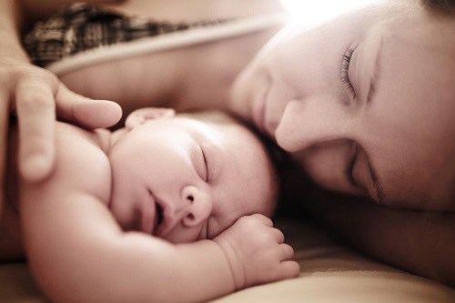 mom cradling baby before getting postpartum massage